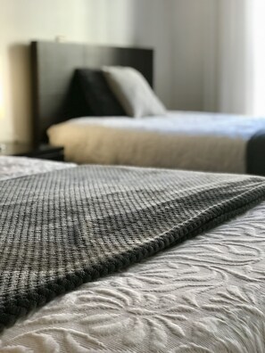 Een bed met een geribbeld grijs deken en een bedspread met een patroon.