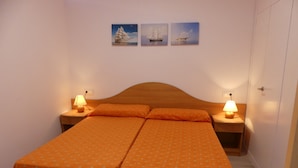 A double bed with matching orange bedding, two bedside tables with lamps, and three framed pictures on the wall. - Alexis Plus  Zeus Salou 9011 (Salou)