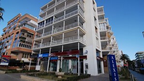A multi-story building with balconies, a sign for 'ALEXIS', and various commercial establishments including a McDonald's and a bank. - Alexis Plus  Zeus Salou 9011 (Salou)
