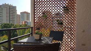 A balcony with wicker furniture, a mesh screen, and potted plants. - See view, 500m from the beach,Aircon,WIFI,terrace (Roquetas de Mar)