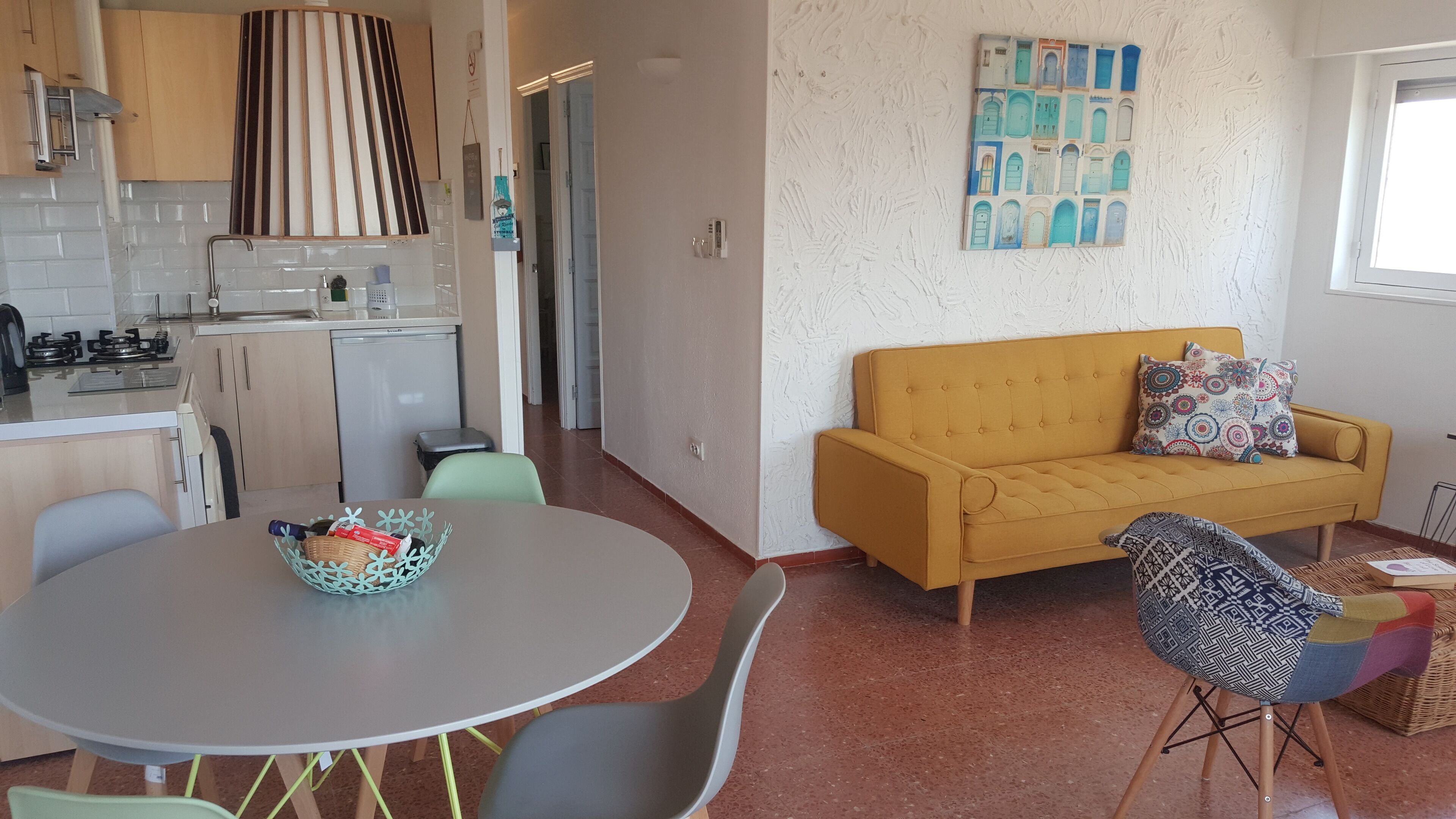 Un espacio habitable pequeño con kitchenette, un sofá y una zona de comedor.