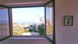 A window with a view of a coastal area, including buildings and palm trees. - See view, 500m from the beach,Aircon,WIFI,terrace (Roquetas de Mar)
