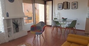 A living room with a fireplace, a dining area with a table and chairs, and a yellow sofa.