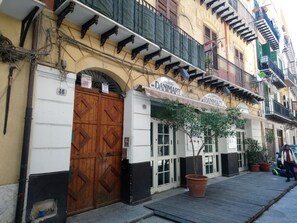 A building with a large wooden door, a sign reading "Danimart," and a potted plant in front.