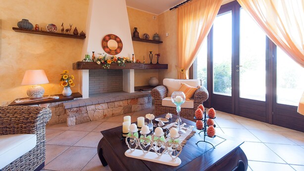 A cozy living room with a fireplace, a sofa, and a coffee table with decorative items. - Villa Rose - Marina Di Mancaversa (Marina di mancaversa)
