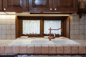 A kitchen with wooden cabinets, a double sink, and lace window treatments. - Villa Rose - Marina Di Mancaversa (Marina di mancaversa)