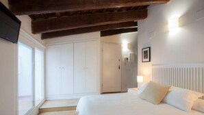 A bedroom with a large bed, white walls, a wooden ceiling, and a door leading to another room. - Singular Stays A. San Vicente II (Valencia / València)