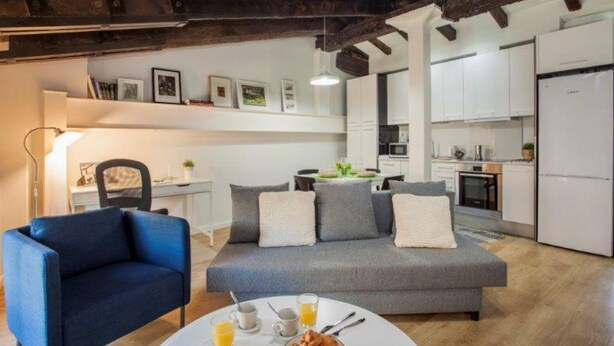 A modern living room with a grey sofa, a blue armchair, and a dining table set with breakfast. - Singular Stays A. San Vicente II (Valencia / València)