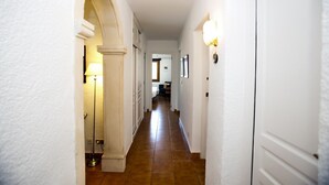 Ein Flur mit weißen Wänden, gefliestem Boden und einer Tür am Ende.