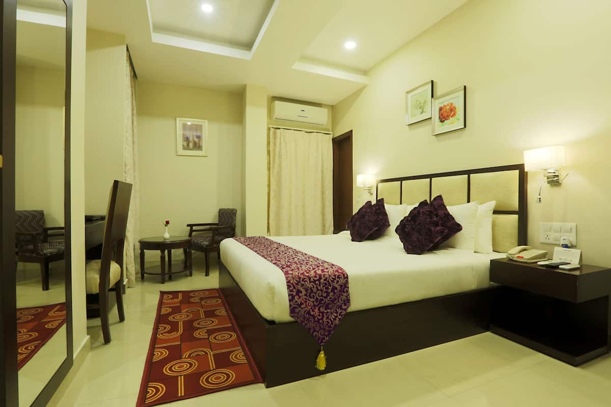 A hotel room with a bed, bedside table, lamp, and a mirror.