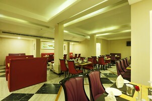 A dining area with booths and tables, featuring a checkered floor pattern and red seating.