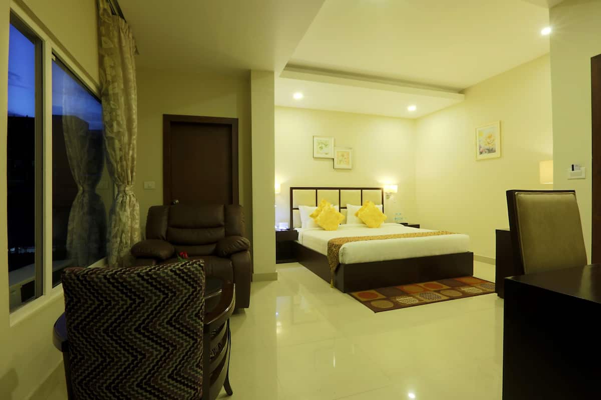 A hotel room with a bed, a desk, a chair, and a window with curtains.