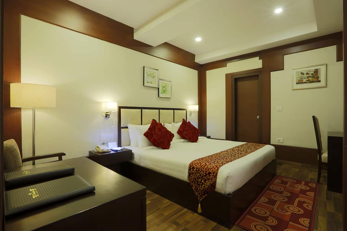 A hotel room with a bed, bedside table, lamp, and a chair.