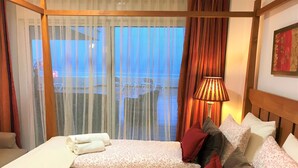 Ein Hotelzimmer mit zwei Betten, einem Fenster mit Vorhängen, einer Lampe und einem Bild an der Wand.