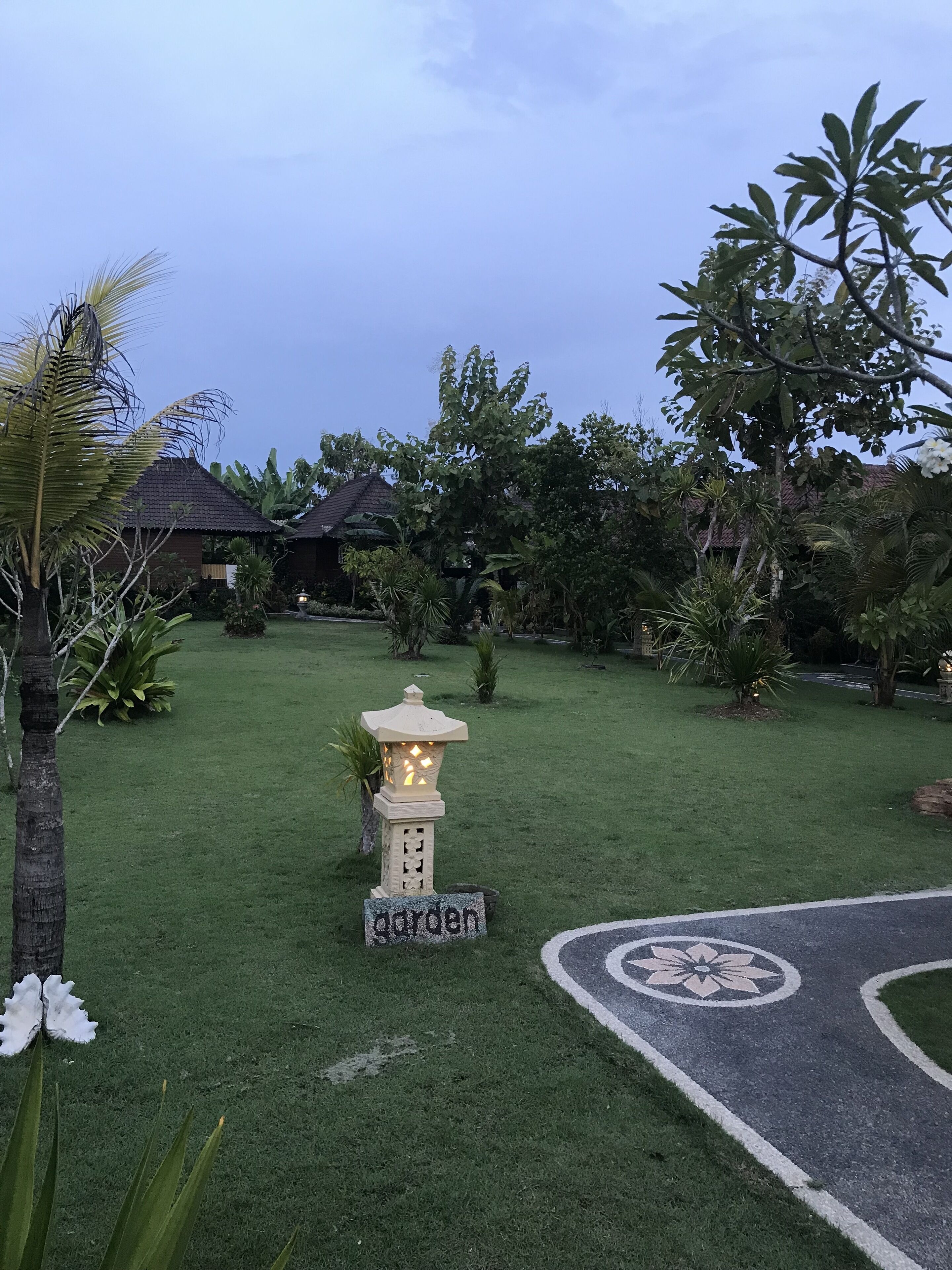 A well-maintained garden with a stone lantern, a sign reading "garden", and a paved path with a flower design.