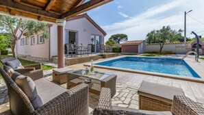 A covered outdoor area with a pool, wicker furniture, and a building with a patio. - Villa Sandra 4+2 with pool, garden & terrace with barbecue & free Wi-Fi (Ližnjan)