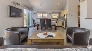 A modern living room with a sofa, a coffee table with a basket and remote controls, and a dining area with chairs and a table. - Villa Sandra 4+2 with pool, garden & terrace with barbecue & free Wi-Fi (Ližnjan)