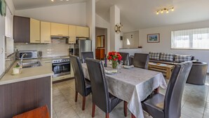 A modern kitchen with a dining area, featuring a central island, a built-in oven, and a coffee machine. - Villa Sandra 4+2 with pool, garden & terrace with barbecue & free Wi-Fi (Ližnjan)