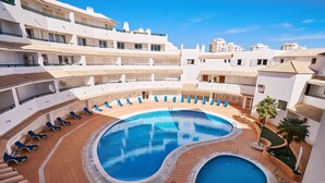 A rooftop pool area with multiple lounge chairs and a central swimming pool. - APARTMENT TANSY DIRECTLY BY THE SEA WITH A DREAM SEA VIEW AND POOL (Armacao de Pera)