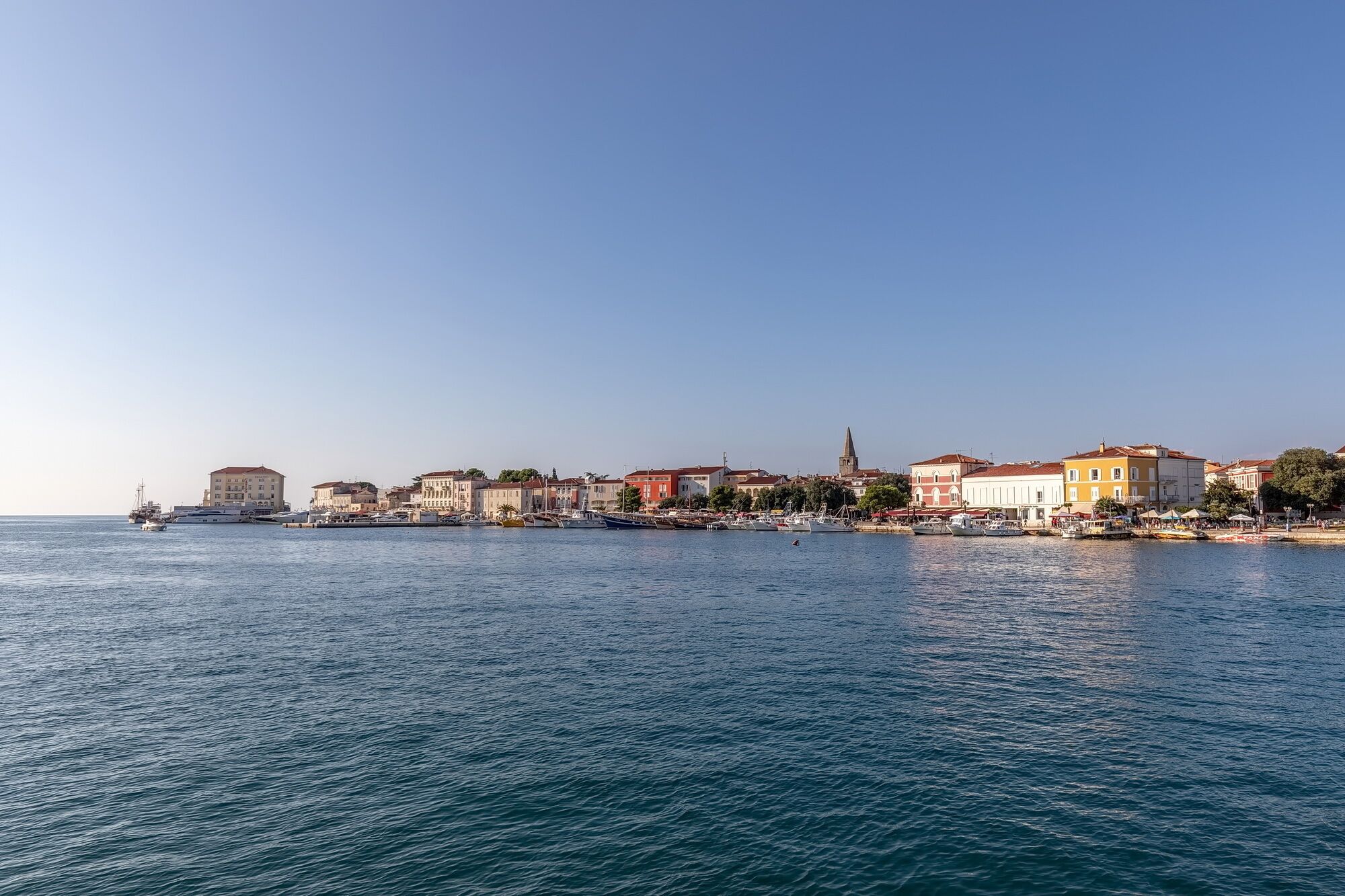 A coastal town with buildings along the waterfront, a clear sky, and calm sea.