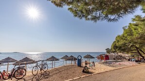 A beachside area with umbrellas, bicycles, and a clear view of the sea.