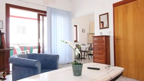 A room with a sofa, a marble table, a potted plant, a wooden cabinet, and a door.