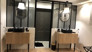 Ein modernes Badezimmer mit zwei Waschbecken, Holzschränken und großen Spiegeln.