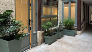 Ein Gebäude mit Innenhof, großen Kübelpflanzen und einer Tür mit Fensterteil.