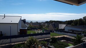 A residential area with modern houses, a clear view of the sea, and a well-maintained garden.