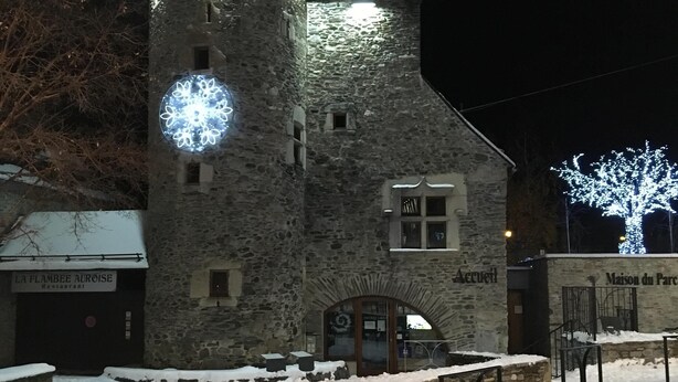 A stone building with a tower, a restaurant sign, and a snow-covered ground.