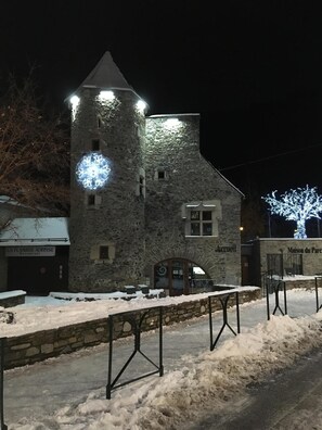 A stone building with a tower, a restaurant sign, and a snow-covered ground.