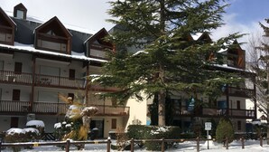 A multi-story hotel with balconies, snow-covered surroundings, and a sign indicating a parking area.
