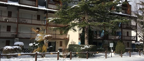 A multi-story hotel with balconies, snow-covered surroundings, and a sign indicating a parking area.