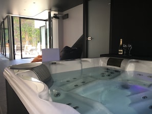 Ein modernes Badezimmer mit einer gläsernen Whirlwanne, einem großen Spiegel und einer Champagnerflasche.