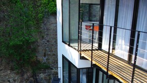 A modern building with a wooden deck, glass walls, and a red chair. - Villa Grand Standing 170m2 :4*, Pool & Jacuzzi PRIVATE: 5 Mn from the beaches (Perros-Guirec)