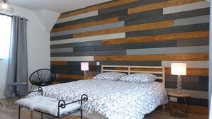 Une chambre à coucher avec un lit, deux tables de chevet avec des lampes, une chaise et une fenêtre avec des rideaux.