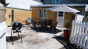 Une terrasse extérieure avec un barbecue, des chaises et une table.