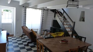 Un salon avec un sol à carreaux, un canapé, une table à manger et un escalier.