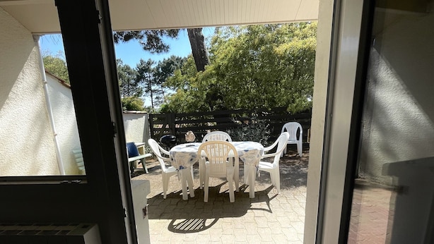 Un espace patio aménagé avec une table et des chaises, un barbecue et une clôture en bois.