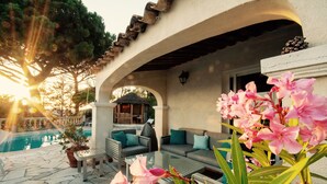 Un patio con piscina, mobiliario exterior y una pérgola.