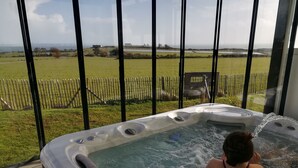 Un bain à remous avec vue sur un champ verdoyant et une clôture en bois.