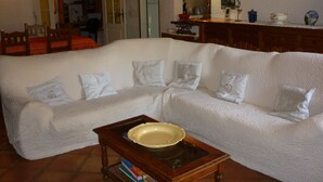 A living room with a white sofa, a coffee table, and a kitchen area in the background.