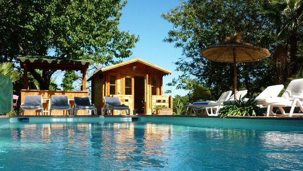 A swimming pool with lounge chairs and a wooden cabin structure.
