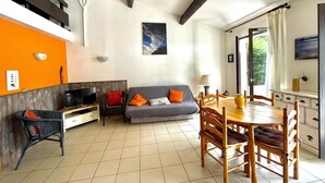 A living room with a sofa, TV, dining table, and chairs.