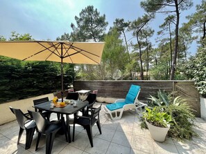 An outdoor patio with a table and chairs, a large umbrella, and potted plants.