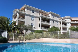 Ett hotell med flera våningar, balkonger, en swimmingpool och en inhägnad trädgårdsyta.