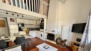 Un soggiorno moderno con un divano, un tavolino e un'area pranzo con sedie. C'è una cucina con elettrodomestici e un camino.