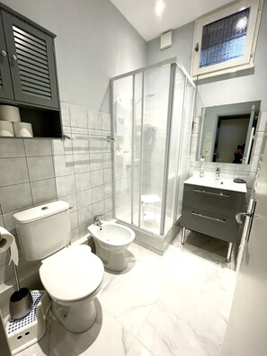 A modern bathroom with a toilet, bidet, and a glass-enclosed shower.