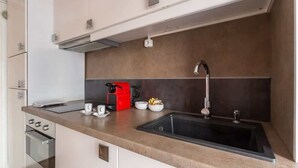 A modern kitchen with a built-in oven, a coffee maker, and a sink.
