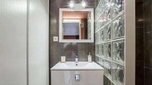 A modern bathroom with a large mirror, a white sink, and a glass partition wall.